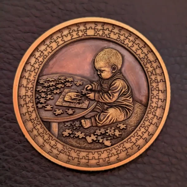 Copper coin with 3D relief baby solving a jigsaw puzzle and puzzle border, engraved with 60W JPT EM7 MOPA fiber laser